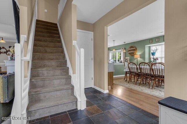 stairway featuring baseboards and stone tile flooring