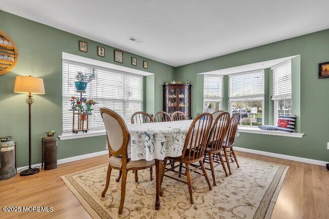 dining space with baseboards, plenty of natural light, wood finished floors, and visible vents