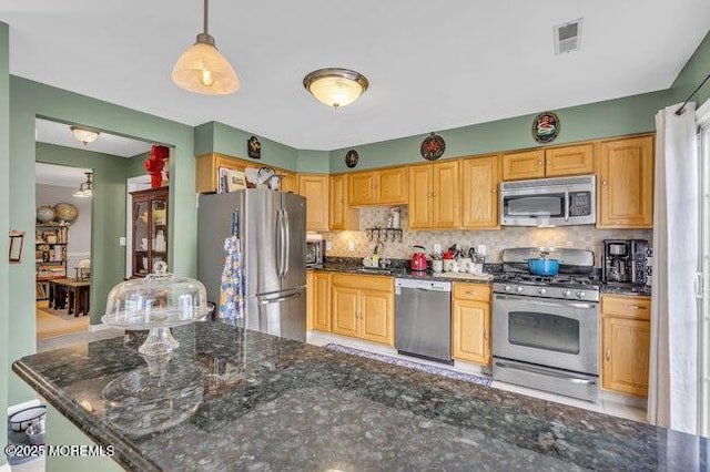 kitchen with appliances with stainless steel finishes, dark stone counters, decorative light fixtures, decorative backsplash, and visible vents