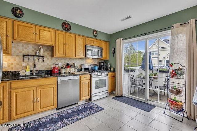kitchen featuring visible vents, light tile patterned flooring, tasteful backsplash, a sink, and appliances with stainless steel finishes
