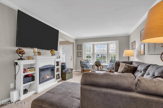 carpeted living room featuring a glass covered fireplace, baseboards, and ornamental molding