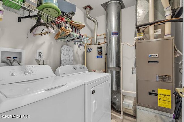 clothes washing area featuring water heater, heating unit, laundry area, and washer and clothes dryer