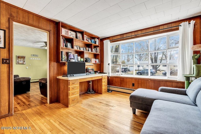 21 Dockage Rd, Bayville, NJ 08721 - home office with built in study area, wooden walls, a baseboard heating unit, light wood-type flooring, and a ceiling fan