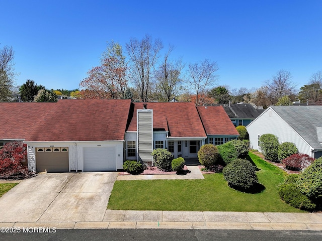 view of front of house featuring an attached garage, driveway, a front lawn, and a chimney