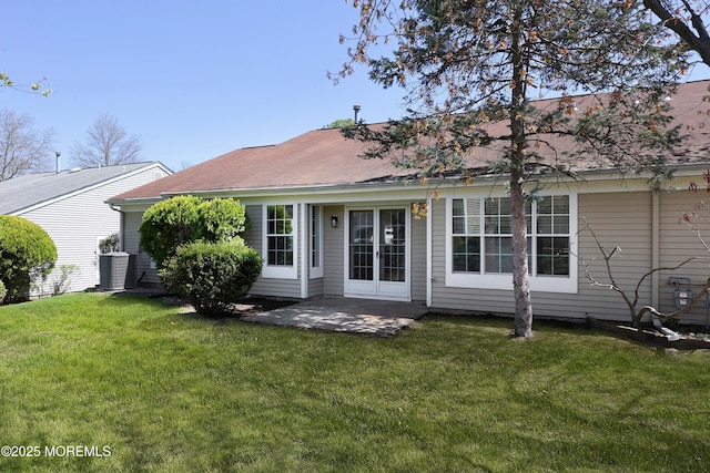 rear view of house with a yard, central air condition unit, a patio area, and a shingled roof