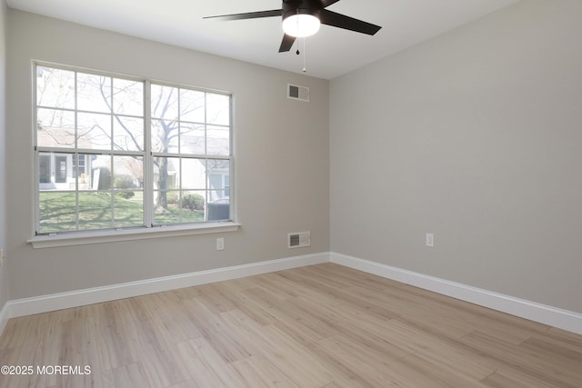 spare room featuring wood finished floors, visible vents, a ceiling fan, and baseboards
