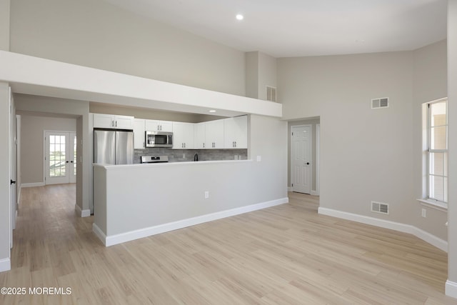 kitchen featuring visible vents, a towering ceiling, and stainless steel appliances