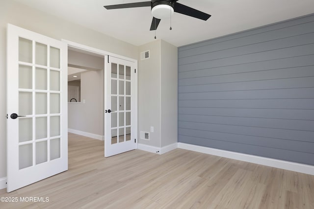 empty room featuring ceiling fan, french doors, light wood-style flooring, baseboards, and visible vents