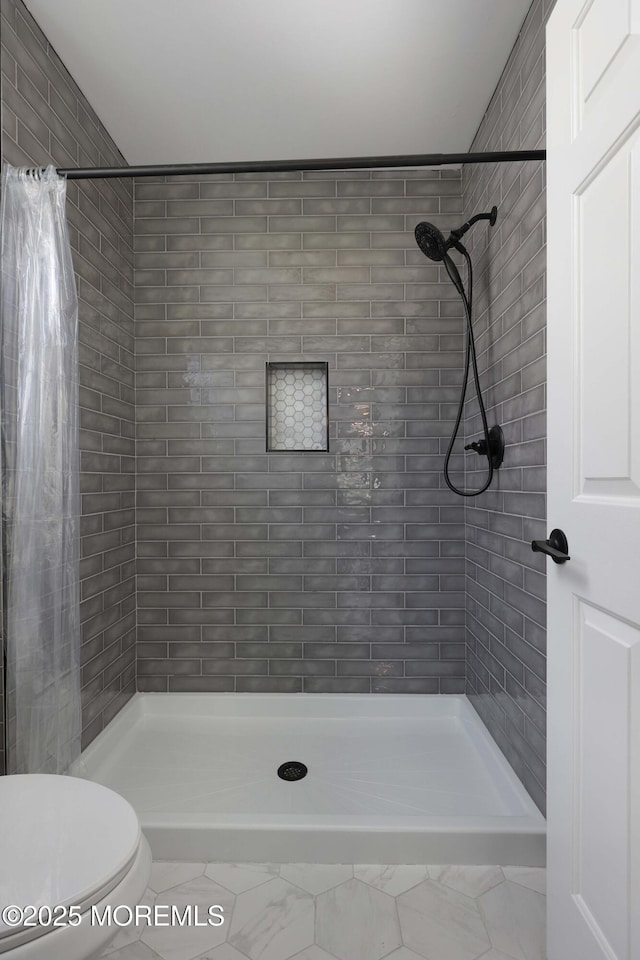 bathroom featuring toilet and a stall shower