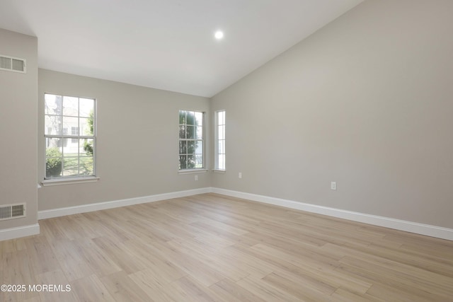 empty room featuring a healthy amount of sunlight, visible vents, and light wood-style flooring
