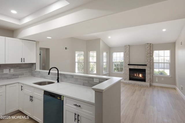 kitchen with light stone counters, tasteful backsplash, a sink, a peninsula, and dishwashing machine