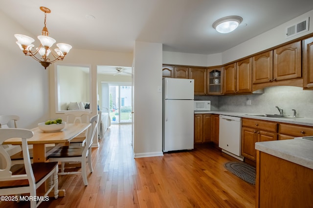 25 Meadow Ave Unit 64, Monmouth Beach, NJ 07750 - kitchen with white appliances, a sink, brown cabinetry, pendant lighting, and light wood-style flooring