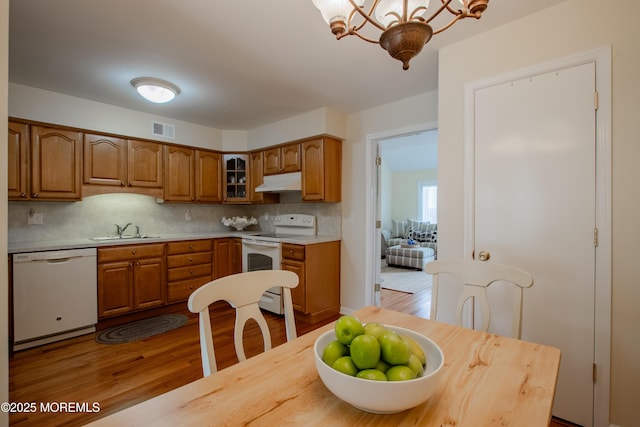 25 Meadow Ave Unit 64, Monmouth Beach, NJ 07750 - kitchen featuring white appliances, a sink, under cabinet range hood, brown cabinetry, and light countertops