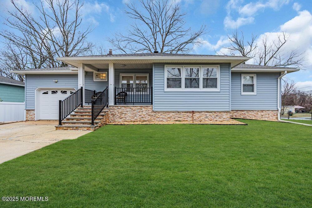 ranch-style house with concrete driveway, covered porch, a front yard, and a garage