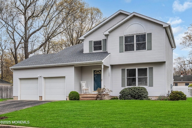 view of front facade with roof with shingles, driveway, fence, an attached garage, and a front yard