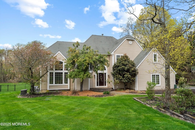 view of front of property featuring roof with shingles, a front yard, and fence