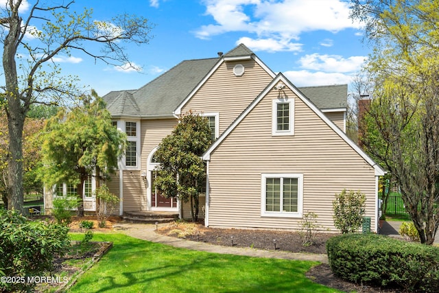 exterior space featuring fence, roof with shingles, and a yard