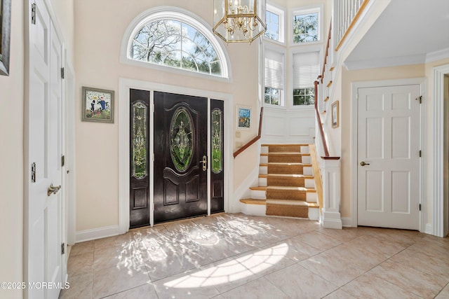 entryway featuring a towering ceiling, a notable chandelier, stairway, and a healthy amount of sunlight