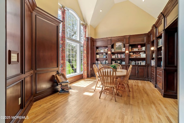 dining space with high vaulted ceiling and light wood-style floors