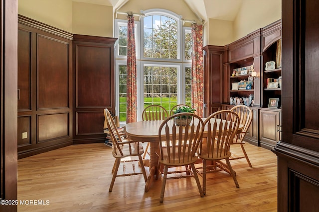 dining room with high vaulted ceiling and light wood finished floors
