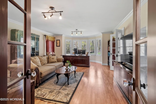 living area featuring light wood-style flooring, crown molding, baseboards, and french doors