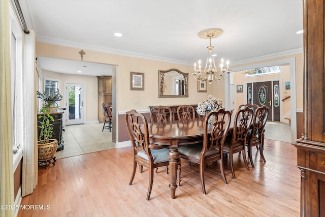 dining area featuring light wood finished floors, baseboards, ornamental molding, and an inviting chandelier