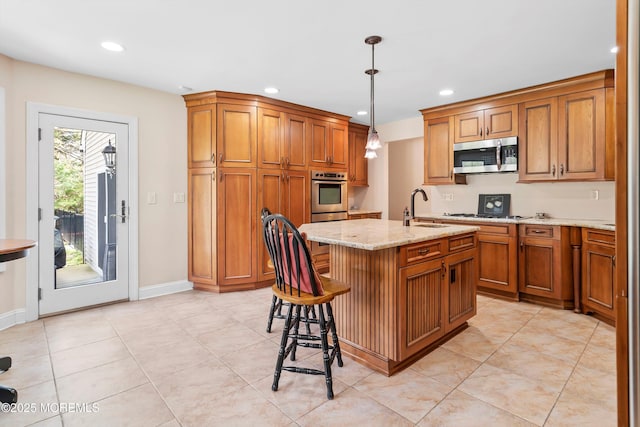 kitchen featuring stainless steel microwave, brown cabinetry, light stone countertops, and a sink