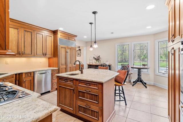 kitchen featuring a sink, light tile patterned flooring, a kitchen bar, appliances with stainless steel finishes, and hanging light fixtures