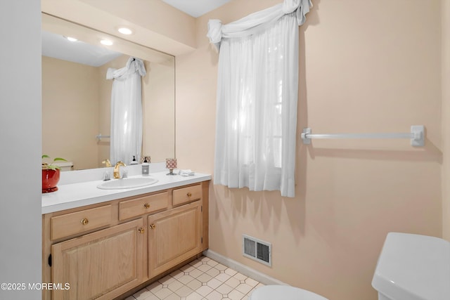 bathroom featuring baseboards, visible vents, toilet, and vanity