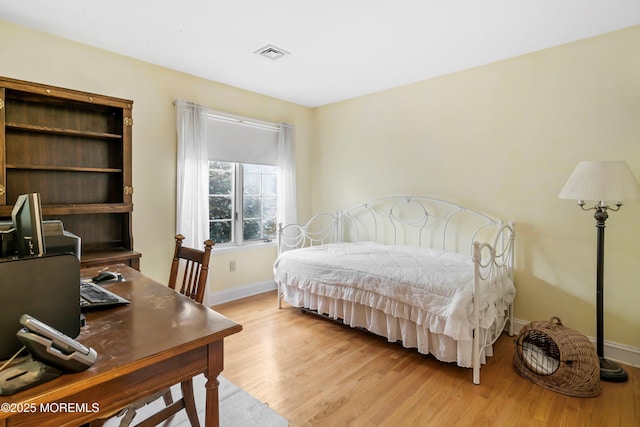 bedroom with baseboards, light wood finished floors, and visible vents