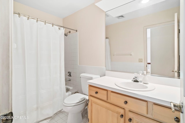 full bath with tile patterned floors, visible vents, toilet, vanity, and tile walls