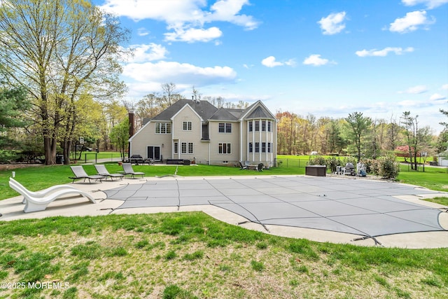 rear view of house featuring a lawn, a patio, and a covered pool