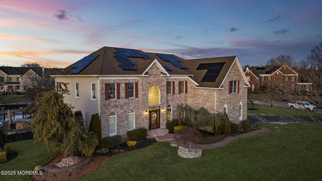 5 Courtney Ct, Freehold, NJ 07728 - view of front facade with roof mounted solar panels, stone siding, and a front yard