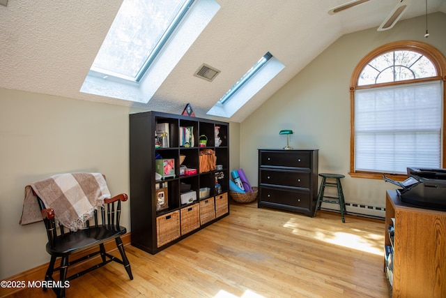 12 Millstream Rd, Cream Ridge, NJ 08514 - interior space with wood finished floors, visible vents, a baseboard radiator, a ceiling fan, and lofted ceiling with skylight
