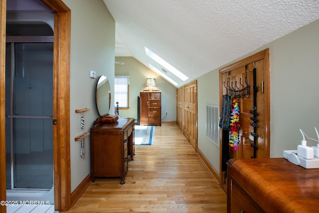 12 Millstream Rd, Cream Ridge, NJ 08514 - hallway with vaulted ceiling with skylight, a textured ceiling, visible vents, baseboards, and light wood-style floors