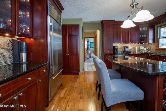 12 Millstream Rd, Cream Ridge, NJ 08514 - kitchen with dark brown cabinets, built in refrigerator, light wood-style flooring, decorative backsplash, and a textured ceiling