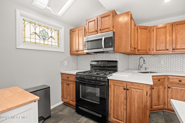 kitchen with a sink, black range with gas stovetop, light countertops, stainless steel microwave, and backsplash