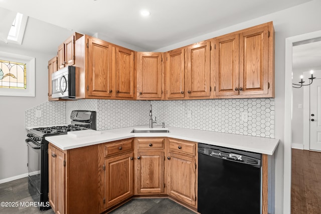 kitchen with backsplash, a sink, light countertops, baseboards, and black appliances