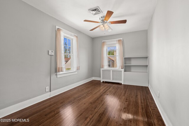 unfurnished room with radiator, ceiling fan, hardwood / wood-style floors, and visible vents