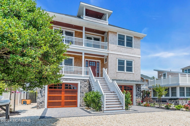beach home featuring stairway, a porch, a balcony, and stone siding