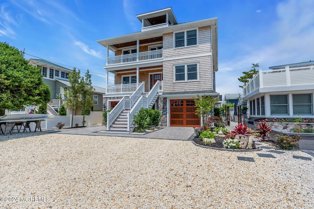 beach home featuring a balcony, driveway, fence, a garage, and stairs