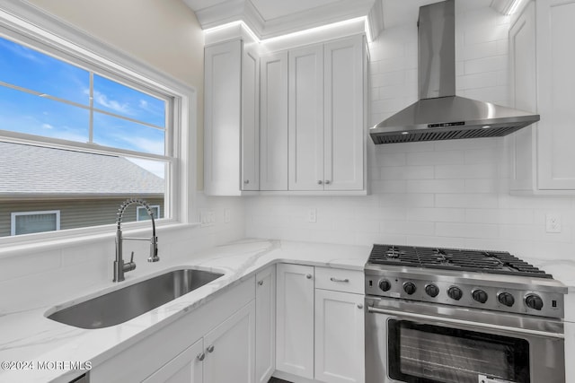kitchen with high end stainless steel range, tasteful backsplash, wall chimney range hood, and a sink