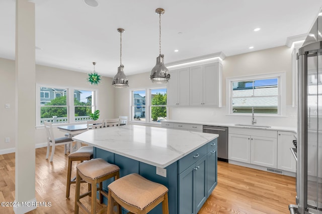 kitchen featuring visible vents, stainless steel dishwasher, a sink, a kitchen island, and a breakfast bar area