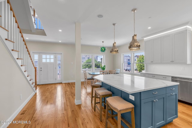 kitchen featuring a kitchen bar, stainless steel dishwasher, a center island, and light wood-style flooring