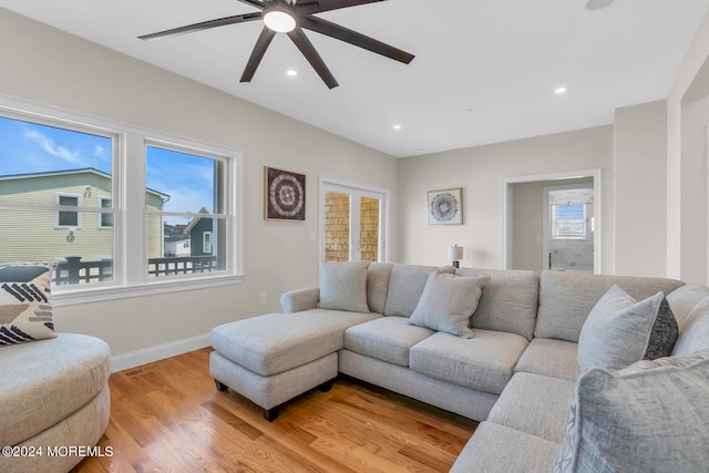 living area with a ceiling fan, baseboards, a wealth of natural light, and light wood-style flooring