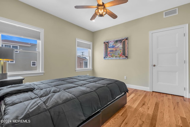 bedroom featuring light wood-style floors, visible vents, baseboards, and ceiling fan