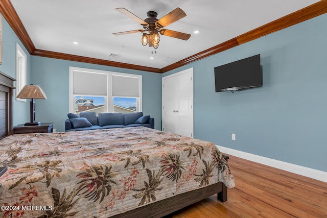 bedroom with wood finished floors, visible vents, crown molding, and baseboards