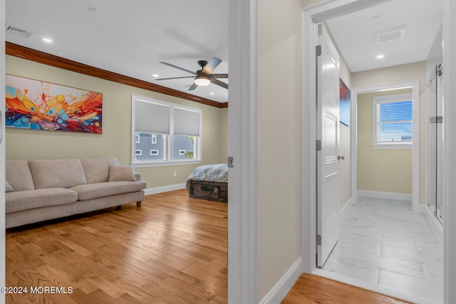 living area with plenty of natural light, visible vents, baseboards, and ceiling fan