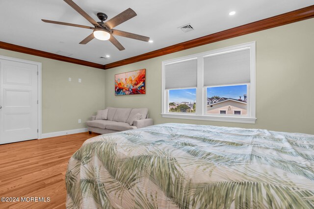 bedroom featuring light wood-style flooring, visible vents, baseboards, and ornamental molding