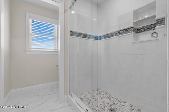 bathroom with a tile shower, marble finish floor, and baseboards